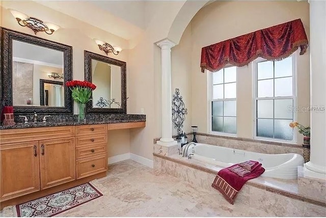 bathroom with tiled bath, vanity, and decorative columns