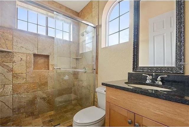 bathroom with toilet, vanity, and an enclosed shower