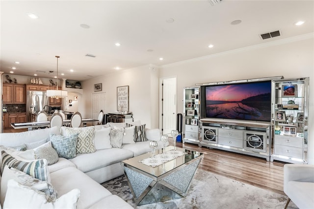 living room featuring ornamental molding and light hardwood / wood-style flooring