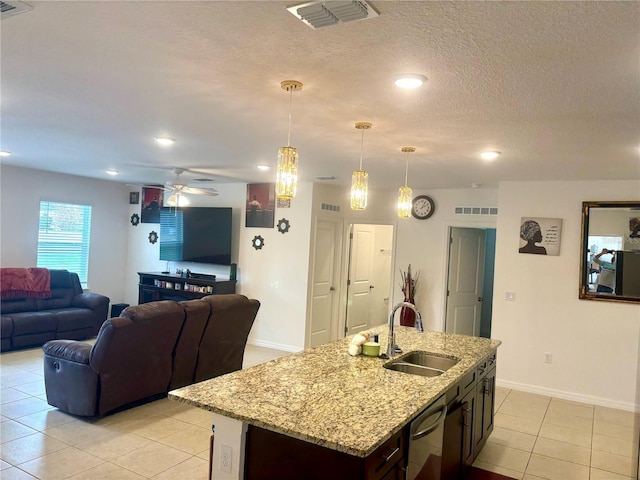 kitchen with an island with sink, ceiling fan, decorative light fixtures, dark brown cabinetry, and sink