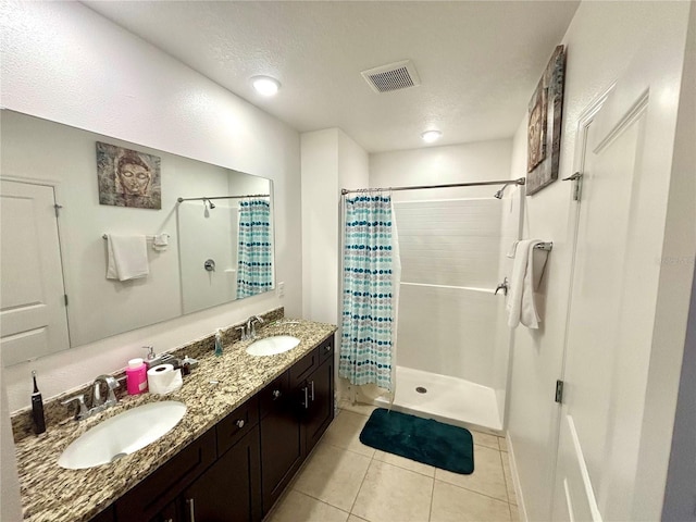 bathroom with a textured ceiling, tile patterned floors, walk in shower, and vanity