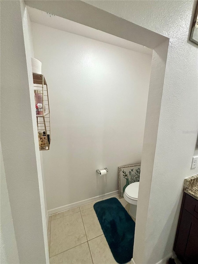 bathroom with toilet, vanity, and tile patterned floors