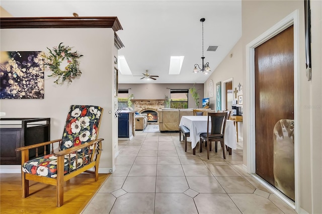 tiled dining room with ceiling fan and vaulted ceiling with skylight