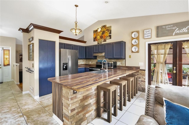 kitchen featuring vaulted ceiling, kitchen peninsula, a kitchen bar, stainless steel appliances, and blue cabinets