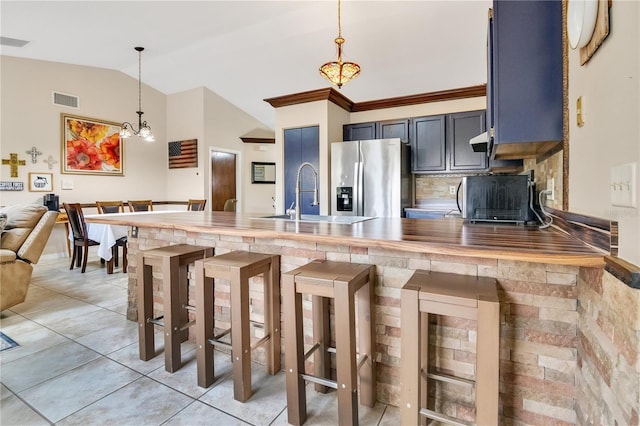 kitchen with vaulted ceiling, pendant lighting, a breakfast bar, kitchen peninsula, and stainless steel fridge with ice dispenser