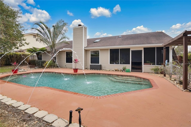 view of pool with pool water feature, a patio, and a sunroom