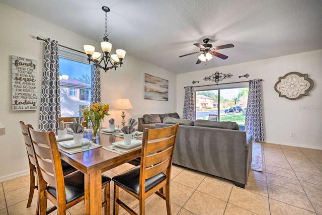 tiled dining room featuring a textured ceiling and ceiling fan with notable chandelier