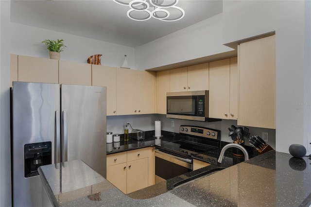 kitchen featuring appliances with stainless steel finishes, dark stone countertops, light brown cabinetry, sink, and kitchen peninsula