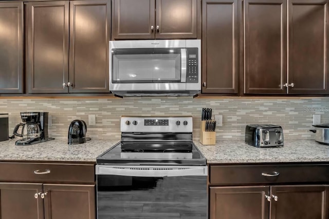 kitchen featuring tasteful backsplash, stainless steel appliances, light stone counters, and dark brown cabinets