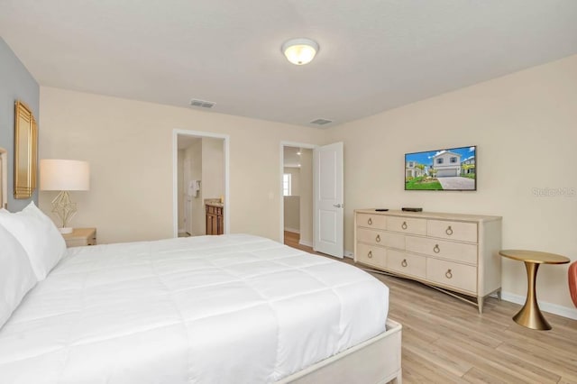 bedroom featuring ensuite bathroom and light wood-type flooring