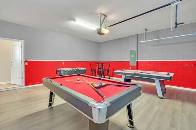 rec room with billiards, electric panel, a textured ceiling, and light hardwood / wood-style floors