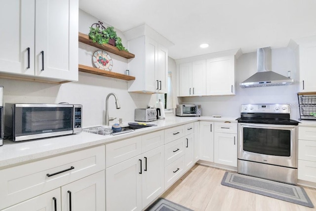 kitchen with sink, white cabinets, wall chimney exhaust hood, stainless steel appliances, and light hardwood / wood-style flooring