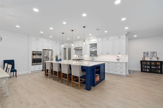 kitchen with white cabinetry, sink, stainless steel appliances, and a center island with sink