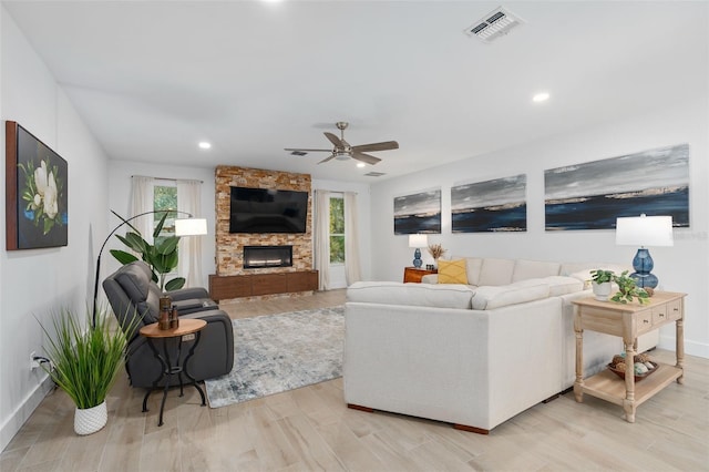 living room featuring a fireplace, ceiling fan, and light wood-type flooring