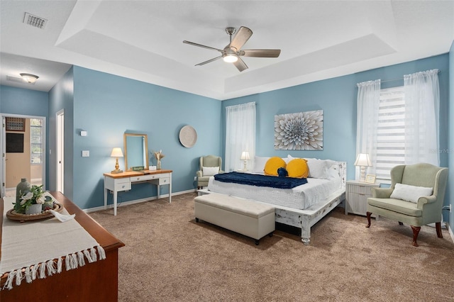 bedroom featuring multiple windows, ceiling fan, and a tray ceiling