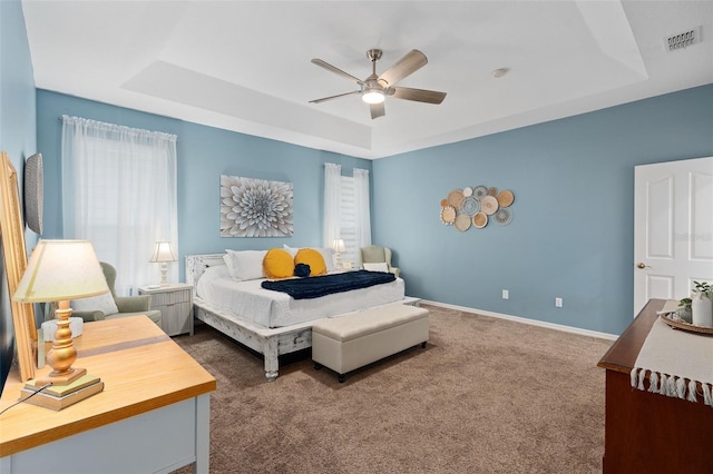 bedroom with multiple windows, ceiling fan, and a tray ceiling