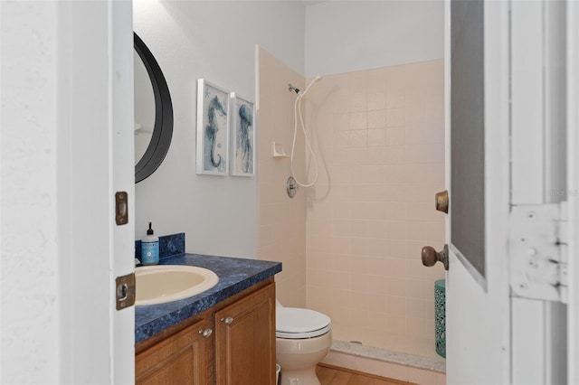 bathroom featuring vanity, toilet, and tiled shower