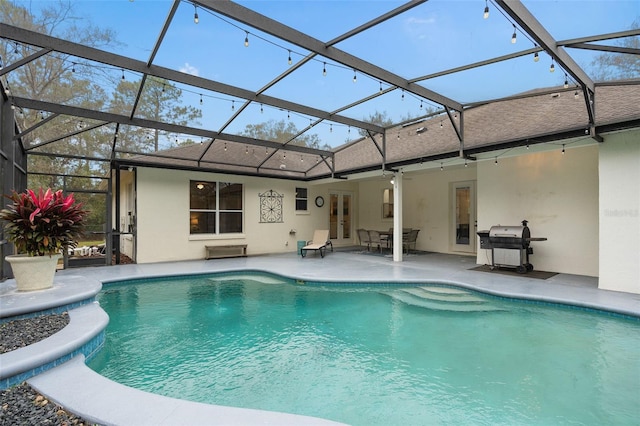 view of swimming pool featuring a grill, a patio area, and glass enclosure