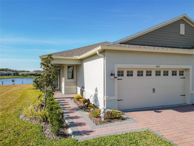 view of front of property featuring a front yard, a garage, and a water view