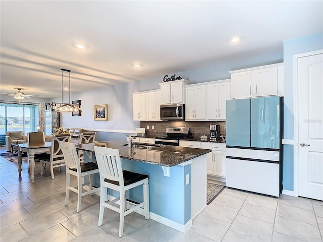 kitchen with light tile patterned floors, white cabinets, backsplash, and appliances with stainless steel finishes