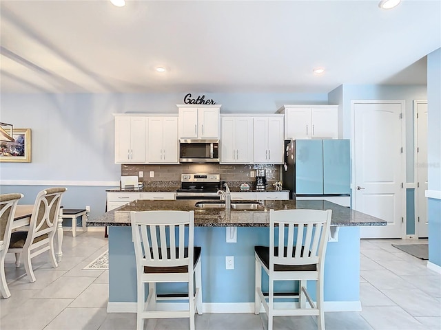 kitchen with stainless steel appliances, sink, a kitchen bar, and a kitchen island with sink