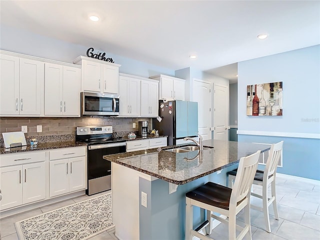 kitchen featuring appliances with stainless steel finishes, an island with sink, white cabinetry, and sink