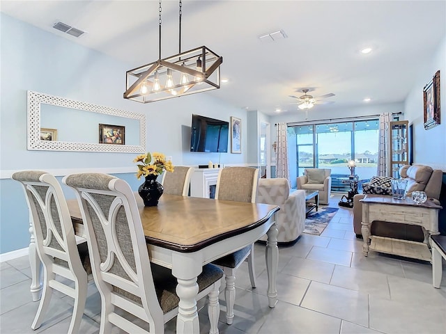 tiled dining area featuring floor to ceiling windows and ceiling fan with notable chandelier