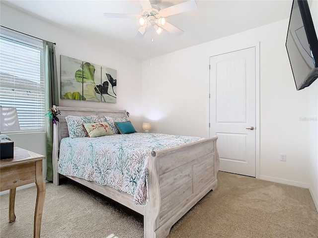 bedroom with ceiling fan, light colored carpet, and multiple windows