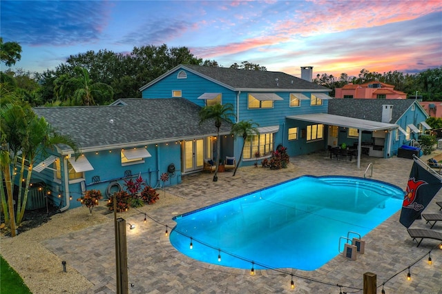 pool at dusk featuring a patio area