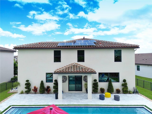 rear view of property featuring a fenced in pool, a patio area, and solar panels