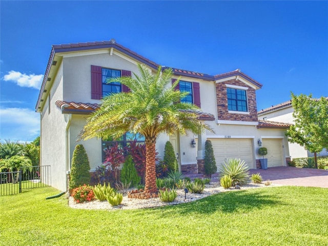 mediterranean / spanish home featuring a garage and a front lawn