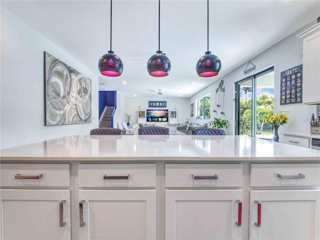 kitchen with decorative light fixtures, white cabinets, and light stone counters