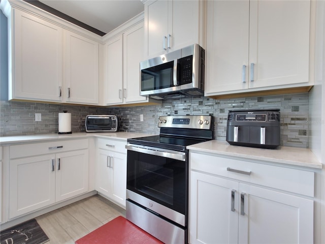 kitchen with light hardwood / wood-style floors, white cabinets, appliances with stainless steel finishes, and tasteful backsplash