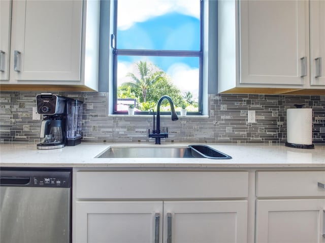 kitchen with sink, white cabinetry, stainless steel dishwasher, and tasteful backsplash