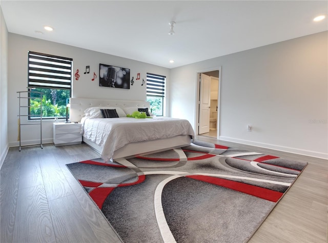 bedroom with ensuite bathroom and hardwood / wood-style floors