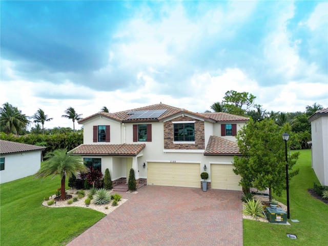 mediterranean / spanish home with a front yard, a garage, and solar panels