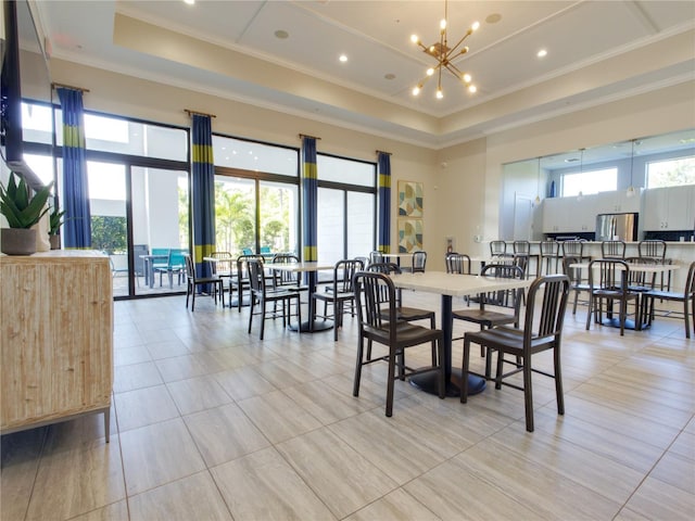 dining space featuring a high ceiling, light tile patterned flooring, ornamental molding, a raised ceiling, and a chandelier