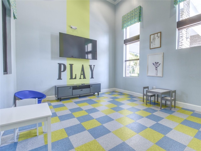 recreation room featuring plenty of natural light and a high ceiling