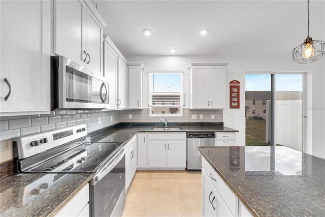 kitchen with white cabinetry, appliances with stainless steel finishes, dark stone counters, pendant lighting, and sink