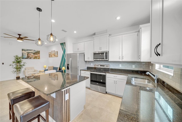 kitchen featuring white cabinets, decorative light fixtures, stainless steel appliances, sink, and backsplash