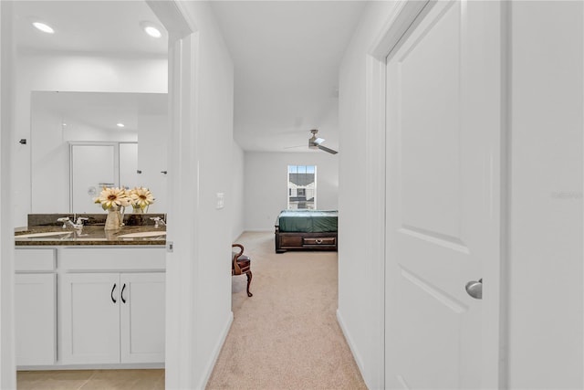 hallway with light colored carpet and sink