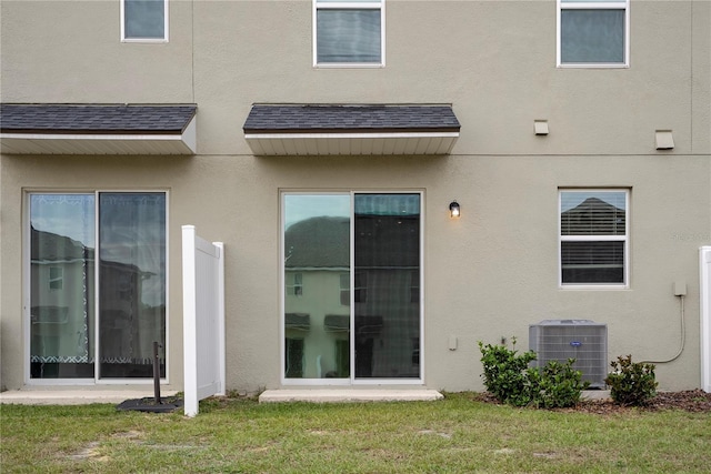 back of house with central AC unit and a lawn