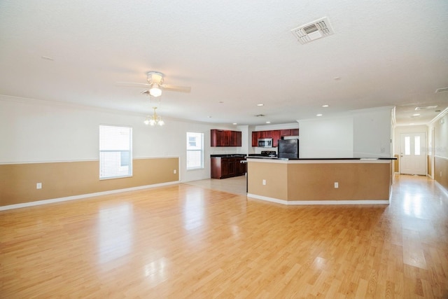 interior space with black refrigerator, light hardwood / wood-style flooring, ceiling fan, ornamental molding, and a kitchen island