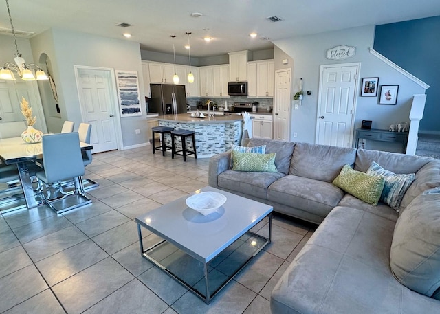 living room with light tile patterned floors, sink, and a chandelier