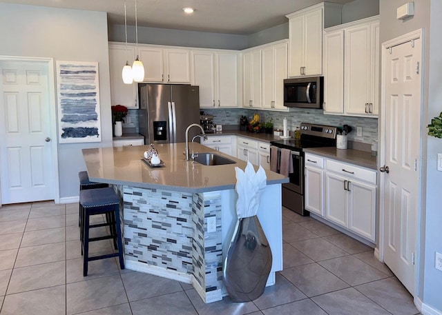 kitchen with decorative light fixtures, sink, a kitchen island with sink, appliances with stainless steel finishes, and white cabinets