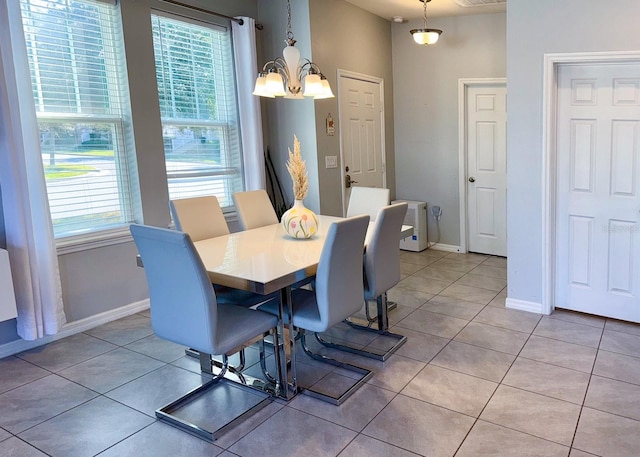 dining space with light tile patterned floors, a wealth of natural light, and an inviting chandelier