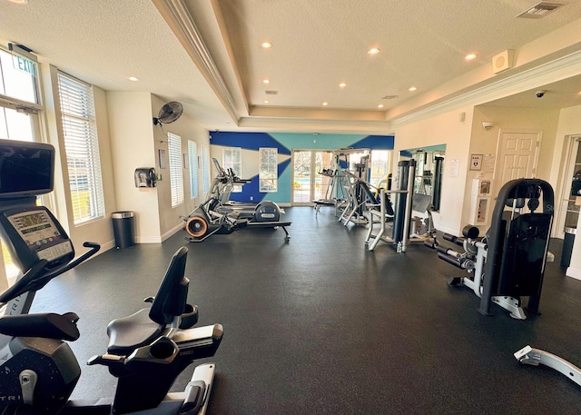 workout area with plenty of natural light, a tray ceiling, and a textured ceiling