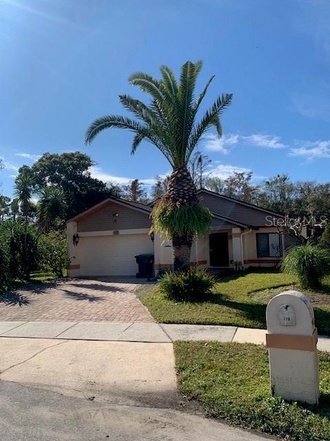 view of front of property featuring a front lawn, decorative driveway, and an attached garage