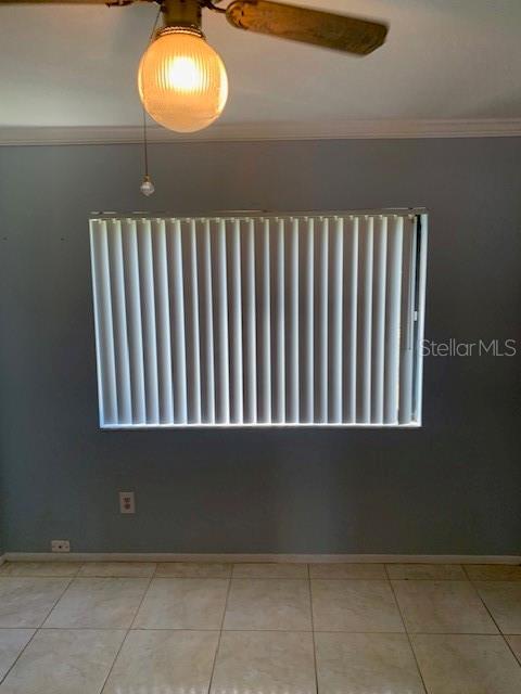 unfurnished room featuring ornamental molding, baseboards, radiator heating unit, and light tile patterned floors