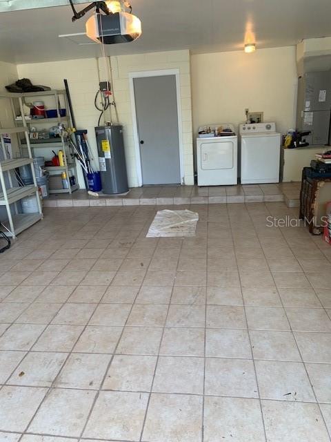 garage featuring a garage door opener, heating unit, electric water heater, and washing machine and clothes dryer